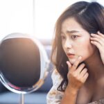 Skin specialist examining common signs of unhealthy skin on patient’s face