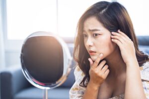 Skin specialist examining common signs of unhealthy skin on patient’s face
